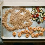Cooked farro, roasted zucchini and seared shrimp spread on a sheet pan to cool before packing
