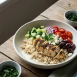 Mediterranean brown rice bowl with lemon chicken, feta, cucumber, tomatoes, and tahini