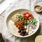 Mediterranean chickpea bowl with roasted chickpeas, quinoa, tomato, cucumber, feta and lemon tahini sauce