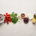 Raw shrimp on ice, cherry tomatoes, spinach, garlic, oregano, kalamata olives, feta, lemon and olive oil laid out