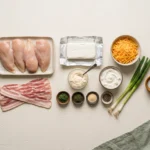 Raw chicken breasts, bacon strips, cream cheese, cheddar and dried ranch herbs laid out for cheesy bacon ranch chicken