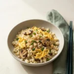 Cauliflower Fried Rice with egg, mushrooms, scallions and sesame in a ceramic bowl