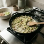 Tuna, green chiles, and zucchini noodles being folded into a creamy skillet sauce