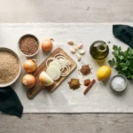 Raw ingredients laid out: dry brown rice, brown lentils, sliced onions, garlic, spices, olive oil and lemon