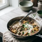 Keto ground beef stroganoff in a stainless skillet with seared mushrooms in a glossy sour cream sauce
