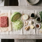 Raw ingredients for keto beef and cabbage skillet: mince, shredded green cabbage, garlic, ginger, soy sauce, sesame oil