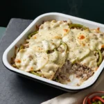 Keto philly cheesesteak casserole baked under melted provolone with green pepper strips showing through
