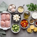 Garlicky greek chicken ingredients including chicken, garlic, lemon, herbs, yogurt, and feta