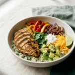 Keto chicken fajita bowl with chicken, peppers, cauliflower rice, avocado, cheese, and sour cream