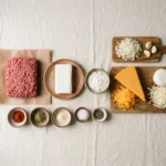 Raw ingredients for keto ground beef casserole: beef, cheddar, mozzarella, cream cheese, onion, garlic