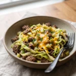 mid-cook keto cheeseburger cabbage skillet with beef and cabbage being stirred in a skillet
