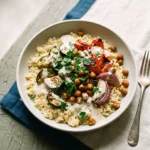Mediterranean couscous bowl with roasted zucchini, pepper, chickpeas, and lemon tahini over fluffy couscous