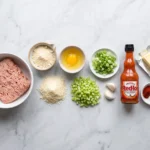 Raw ingredients for buffalo chicken meatballs including ground chicken, almond flour, egg, celery, and hot sauce