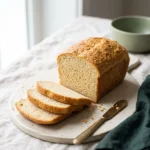 Sliced loaf from this keto sandwich bread recipe on a pale ceramic board, showing a soft fine crumb