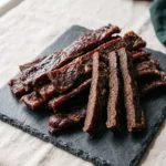 Carnivore beef jerky recipe strips piled on a slate serving board