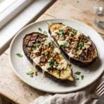 Roasted eggplant with lemon tahini, toasted pine nuts, and parsley on a ceramic plate