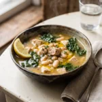 High protein white bean chicken kale soup served in a rustic bowl with lemon and olive oil