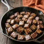 Carnivore garlic butter steak bites glossy in a cast iron skillet