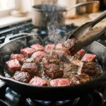 Sirloin cubes searing in a hot skillet for carnivore garlic butter steak bites