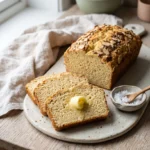 Sliced almond flour keto bread on a wooden board with butter melting on the front slice