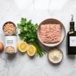 Raw ground chicken, egg, white beans, lemon and parsley for Mediterranean chicken meatballs